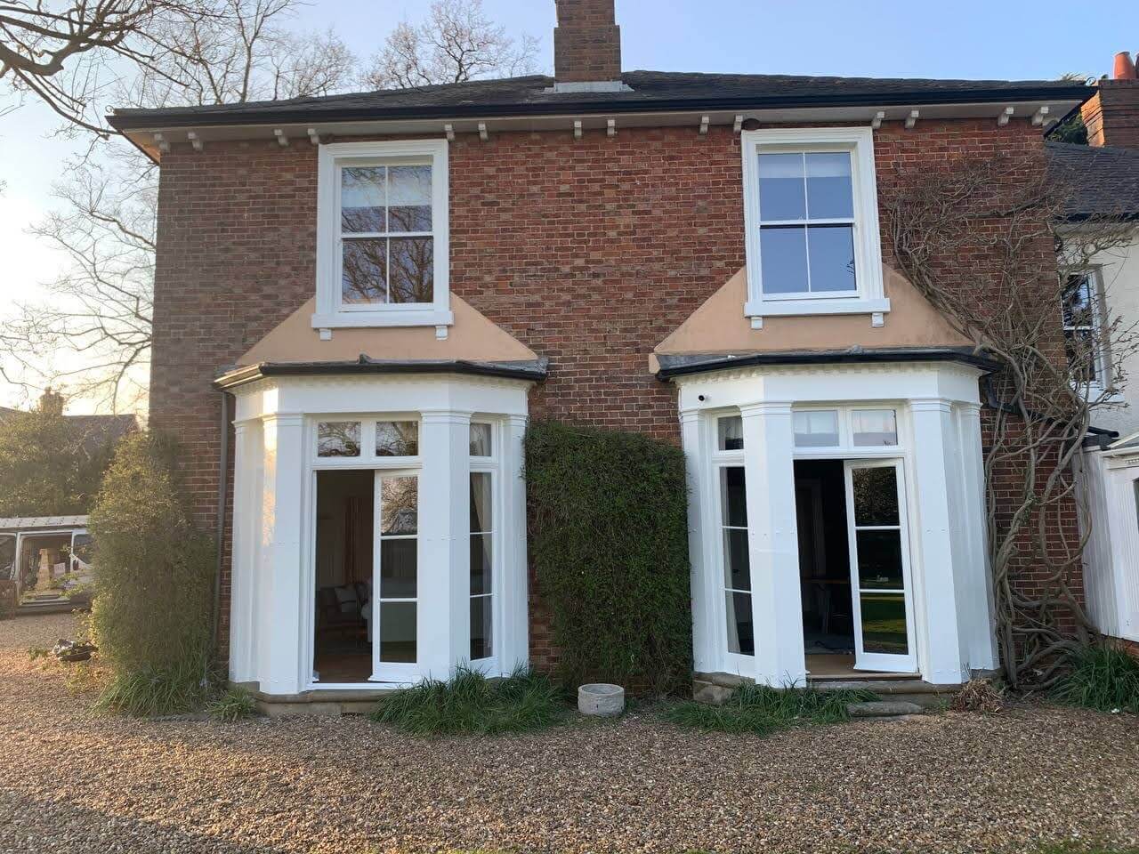 Two-storey brick house with a pair of ground-floor bay windows painted white