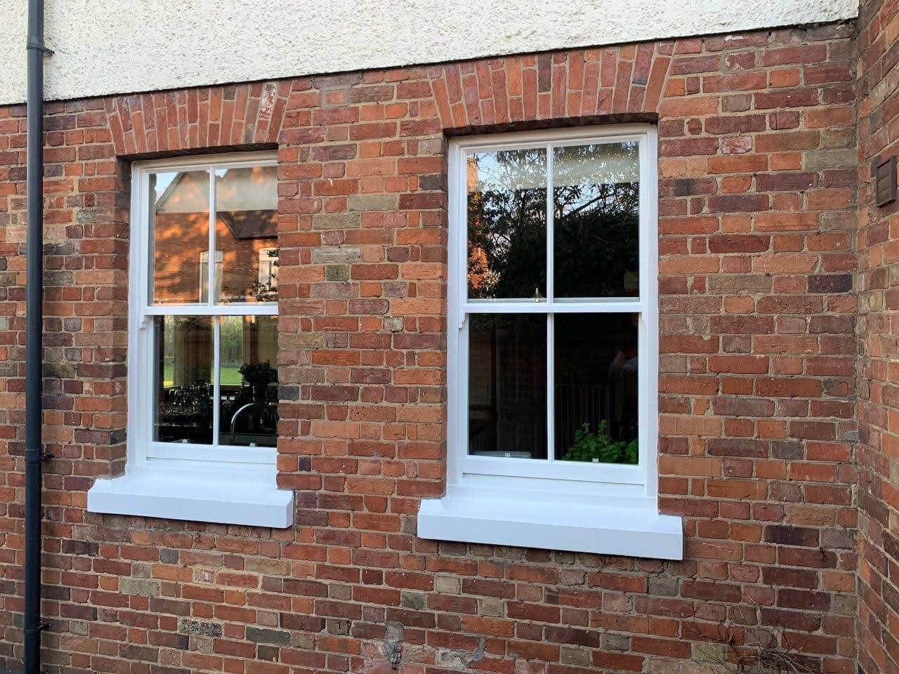 Pair of two-over-two sash windows in a red brick wall after reglazing