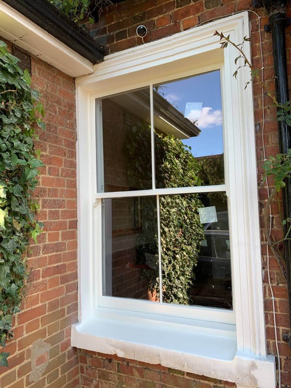 Close-up of a one-over-one Victorian sash window reflecting the sky