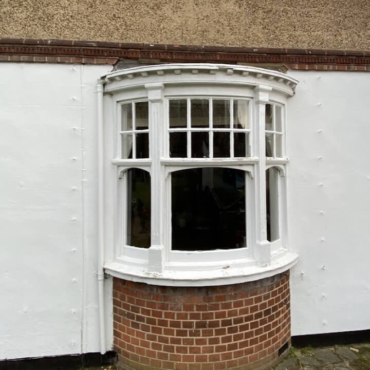 Curved bow window with three sashes in a white rendered wall