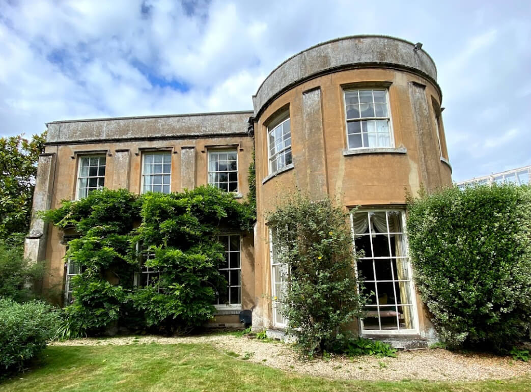Rendered Regency house with a curved bow front and tall glazing-bar sash windows