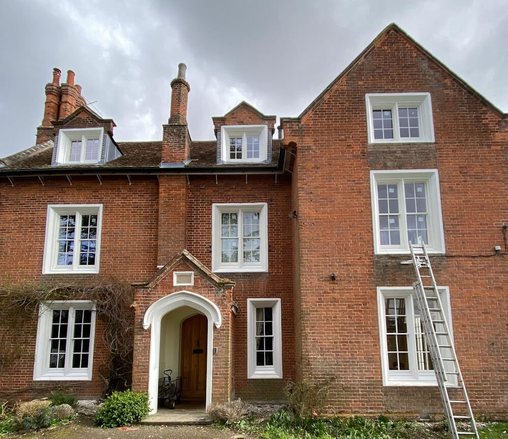 Tall red brick Georgian house with many sash windows and a ladder against the wall