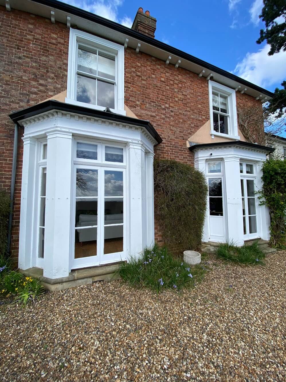 Brick house with an angled bay window and sash windows above