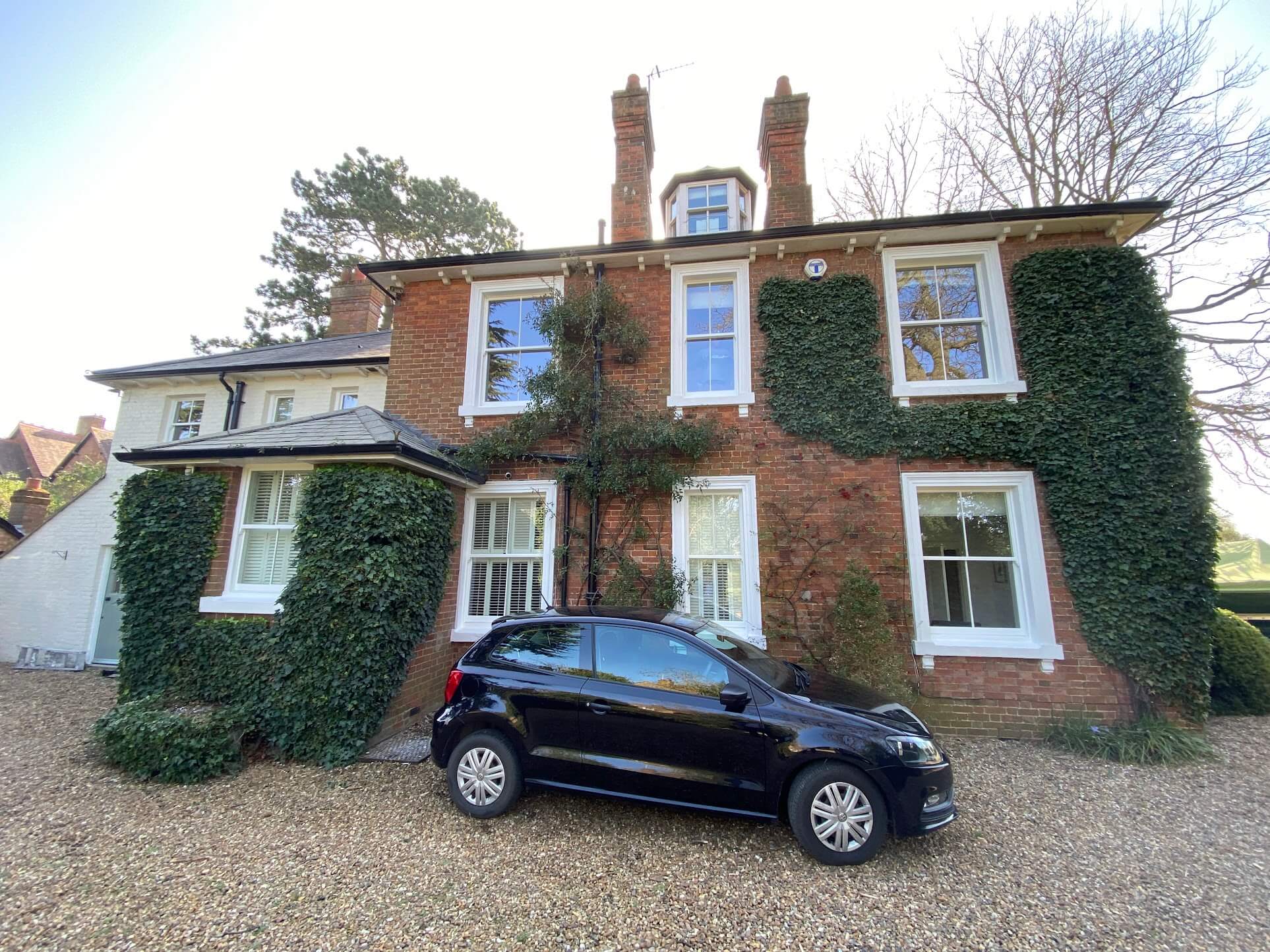 Ivy-clad brick house with freshly painted white sash windows on three floors
