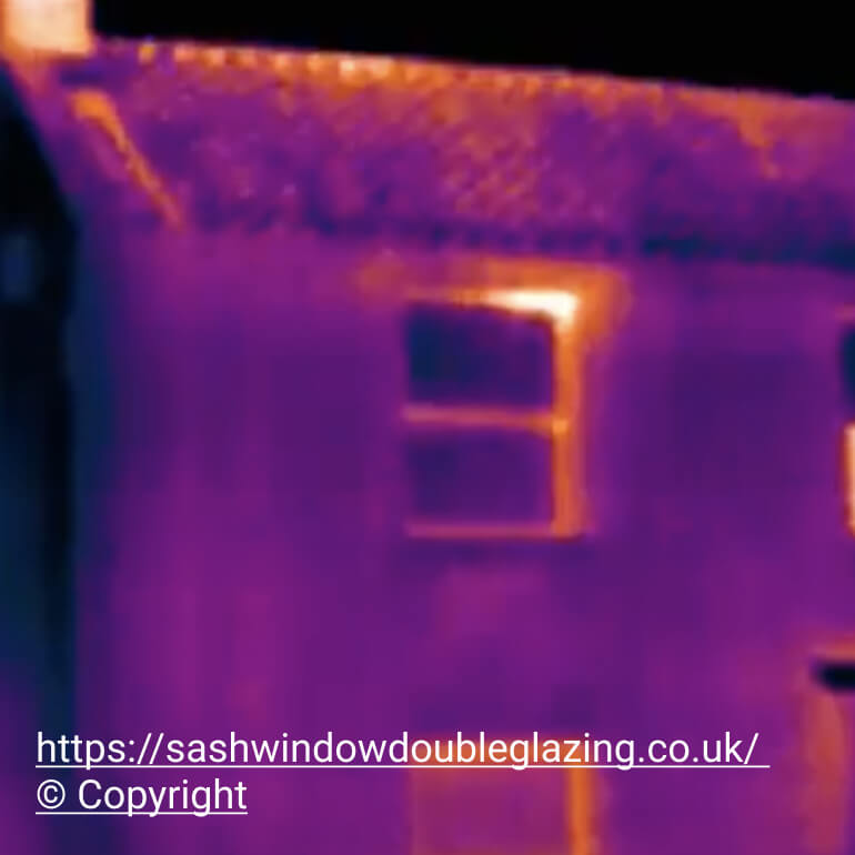 Thermal image of a house at night with heat escaping through a window